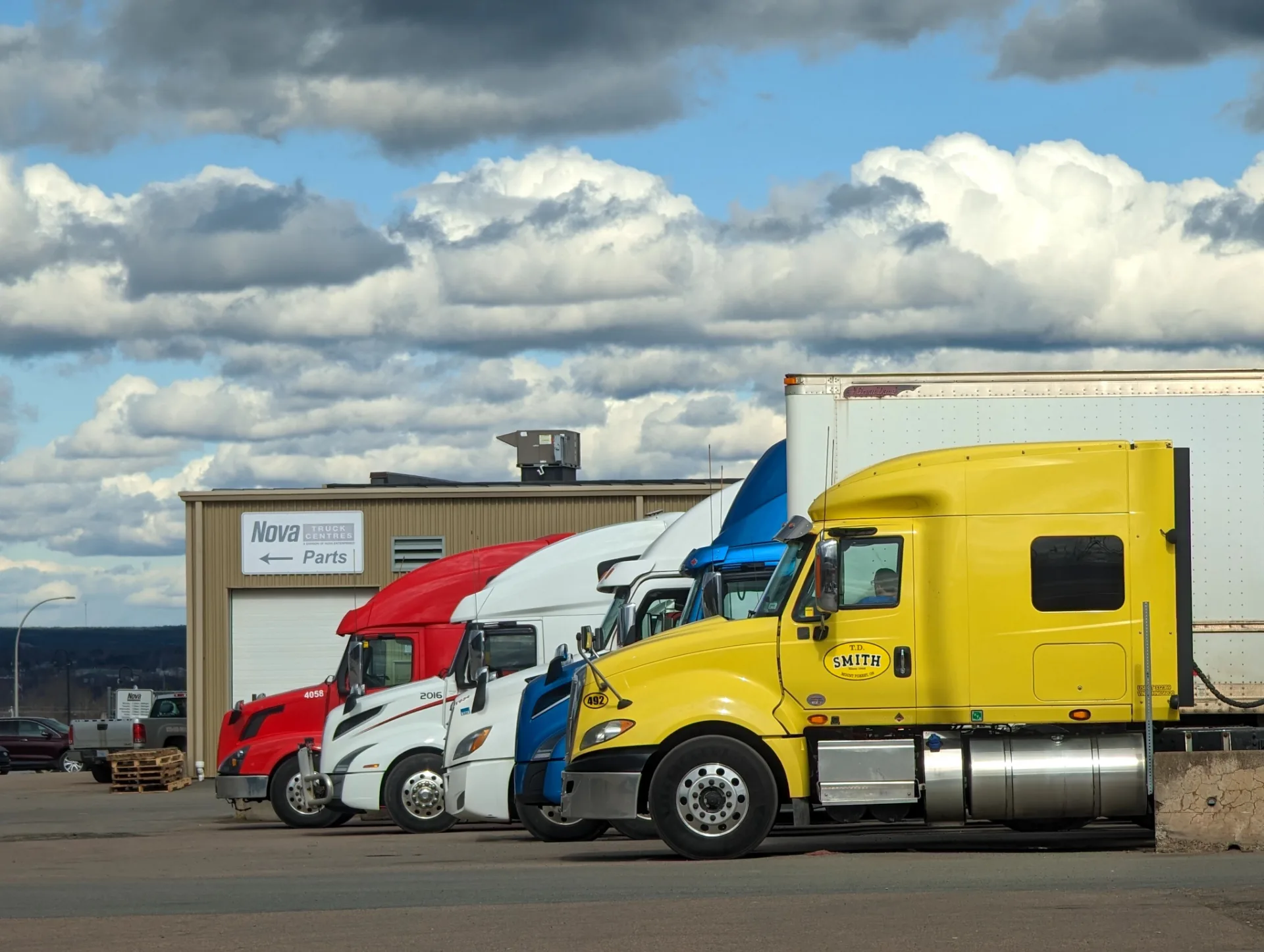 Row of colorful semi trucks parked at a truck service center
